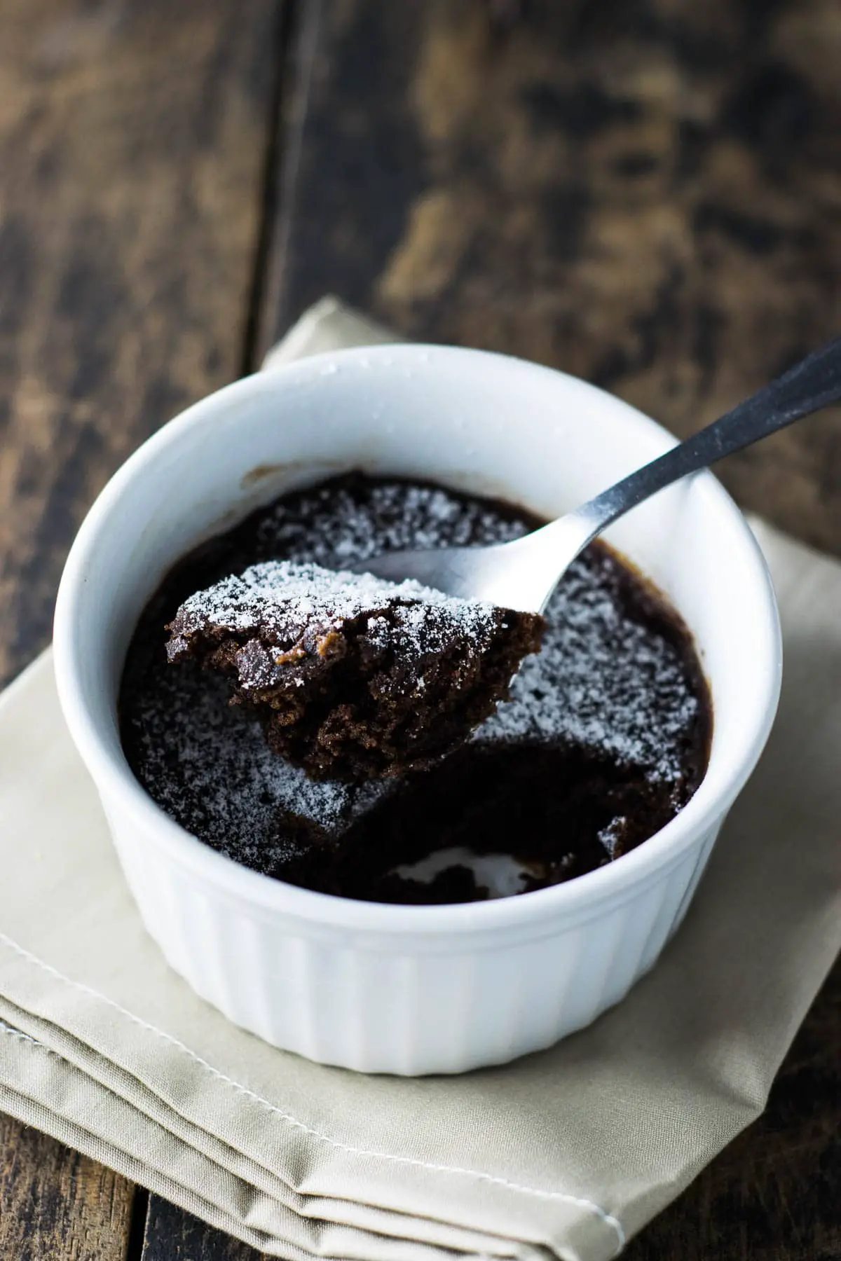 Microwave brownie make in white ramekin, being spooned out to be eaten