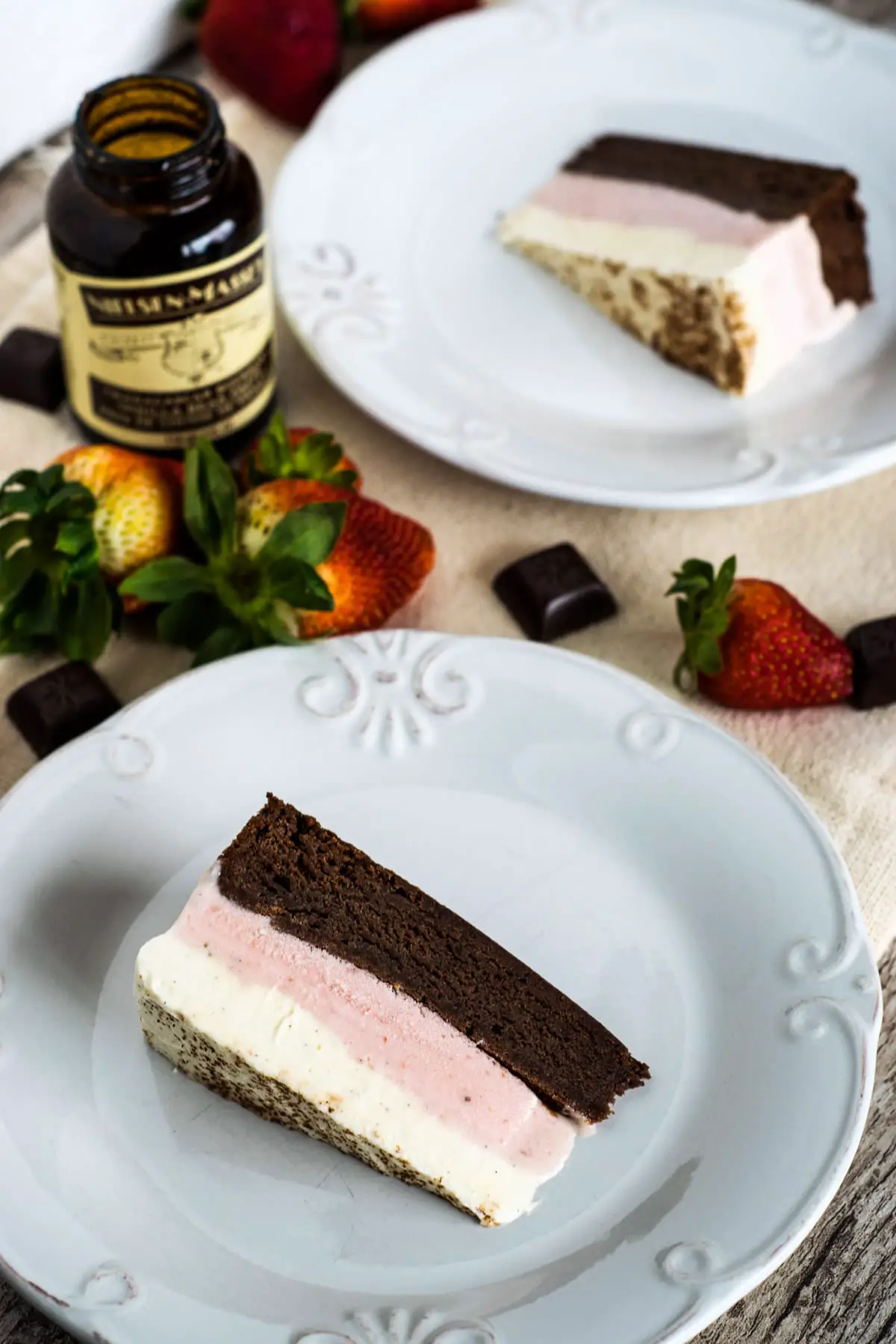 Slices of Neapolitan ice cream cake served on white plates showing the characteristic layers - chocolate, strawberry and vanilla