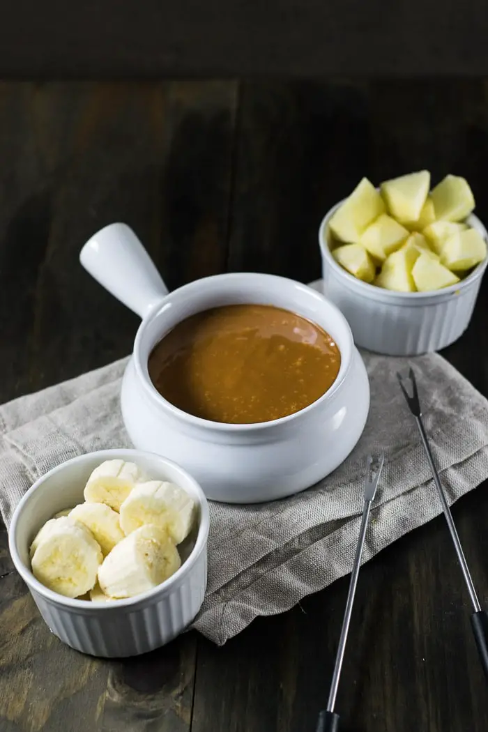 Dulce de leche fondue served in a ceramic pot with apples and bananas 