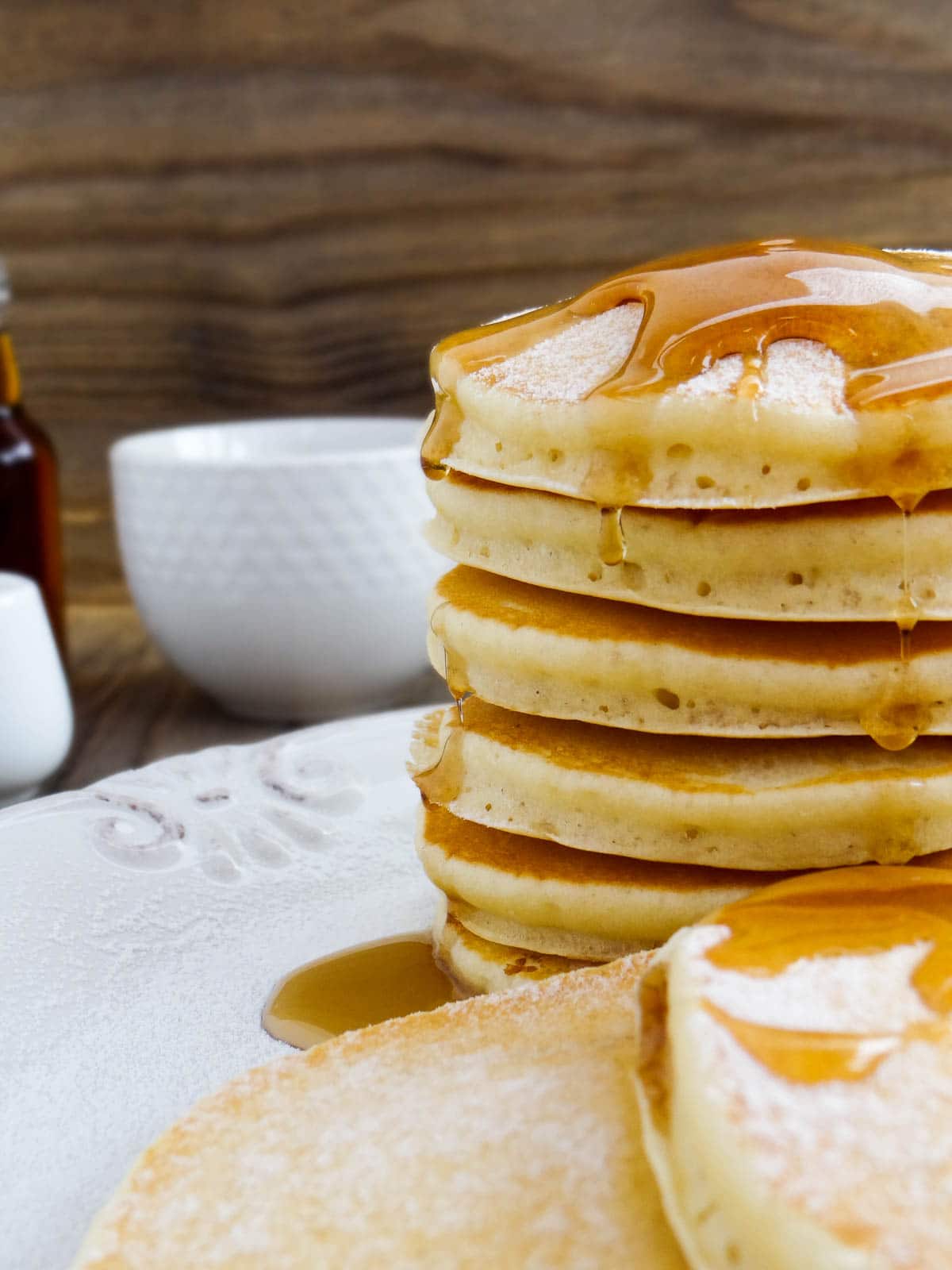 Stack of homemade pancakes with syrup poured over and dripping on the side