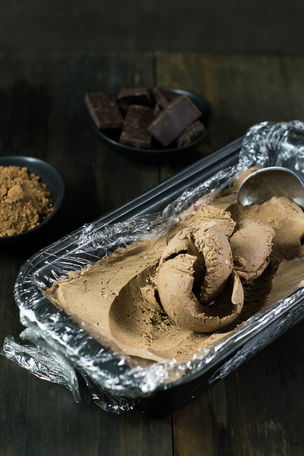 No-Churn Chocolate Ice Cream being scooped from inside a loaf pan lined with plastic wrap