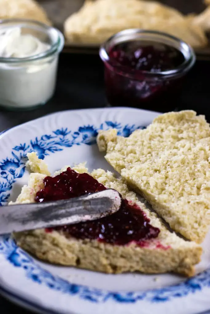 Scone opened in half with raspberry jam spread over bottom half